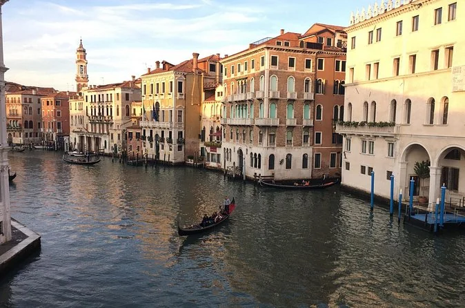 A wide canal lined with old houses in warm colours, a gondola gliding in the middle distance