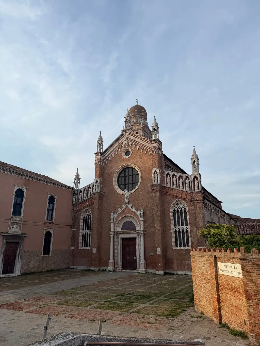 The brick Gothic facade of the Madonna dell'Orto church in Cannaregio under a clear sky
